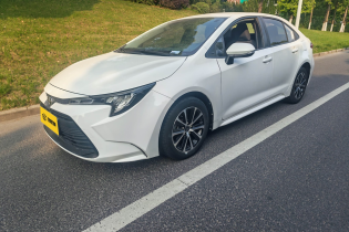White Toyota compact four-door sedan fitted with dark multi-spoke alloy wheels outdoors