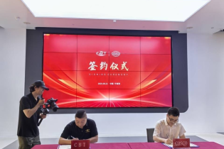 CBT co-founder Zhuqi and COSCO signing documents at a signing ceremony with a large red screen displaying "Signing Ceremony" in the background, and a cameraman filming.