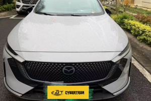 Silver Mazda front fascia featuring centered brand emblem and sport mesh grille on roadside