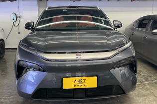 Close-up front fascia of grey BYD EV with seamless LED light strip and yellow display plate indoors