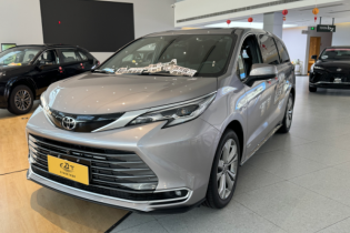 A sleek silver Toyota Sienna minivan on display in a bright dealership showroom, accented with festive red Chinese New Year lanterns.