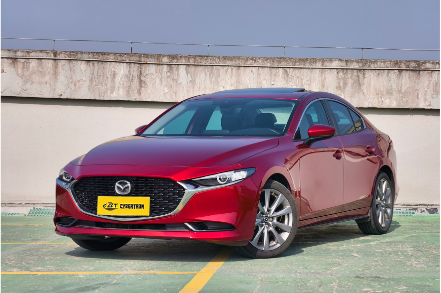Soul red Mazda 3 sedan three-quarter front shot parked on rooftop parking lot under clear blue sky