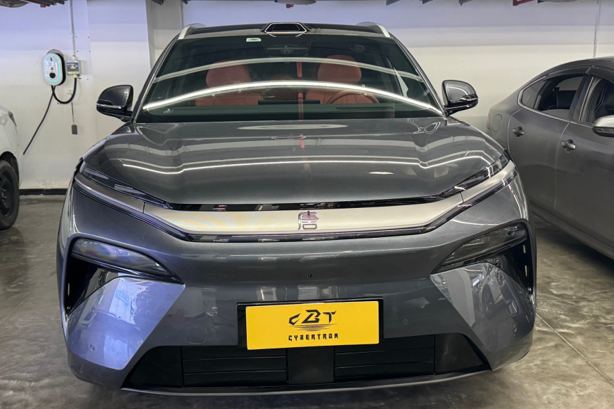 Close-up front fascia of grey BYD EV with seamless LED light strip and yellow display plate indoors
