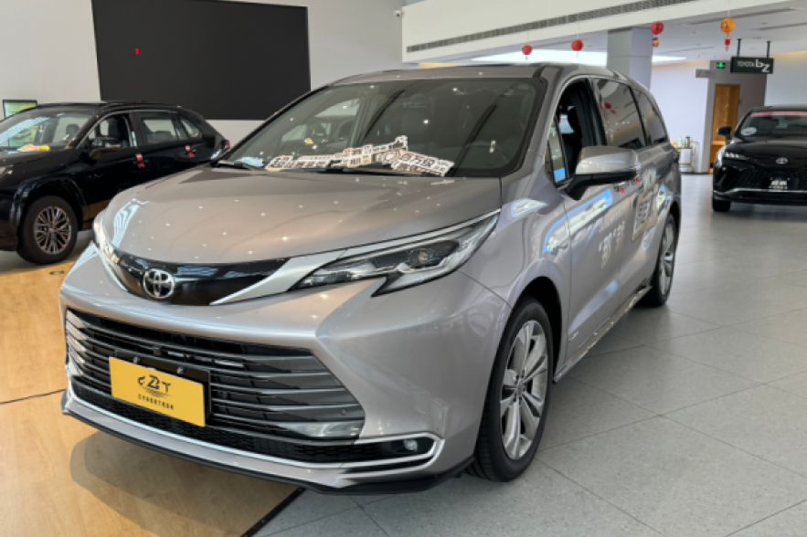 A sleek silver Toyota Sienna minivan on display in a bright dealership showroom, accented with festive red Chinese New Year lanterns.