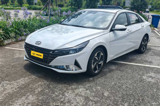 Sleek white Hyundai compact sedan with dark grille, sharp LED headlights and multi-spoke alloy wheels