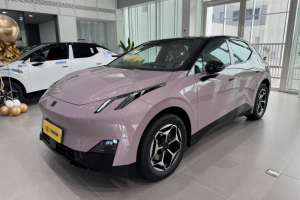 Light pink pure electric hatchback in indoor showroom, front-side view with futuristic LED lights, alloy wheels and yellow license plate.