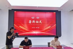 CBT co-founder Zhuqi and COSCO signing documents at a signing ceremony with a large red screen displaying "Signing Ceremony" in the background, and a cameraman filming.