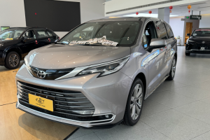 A sleek silver Toyota Sienna minivan on display in a bright dealership showroom, accented with festive red Chinese New Year lanterns.