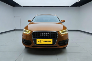 Orange Audi Q3 compact SUV in indoor showroom, front-side view with alloy wheels, iconic grille and yellow license plate.