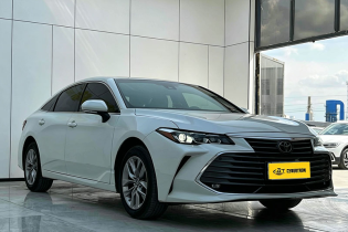 White Toyota Avalon full-size sedan three-quarter front view displayed inside bright indoor car photography studio