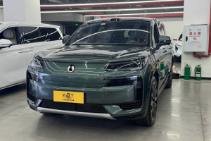 Dark green Denza N9 plug-in hybrid SUV front view parked in indoor used car dealership, sleek closed grille design