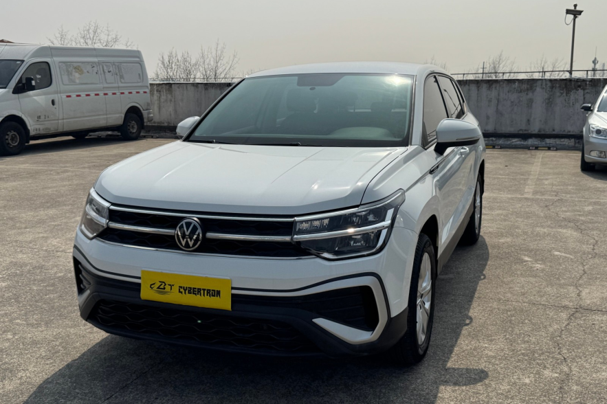 Glossy white VW crossover with chrome grille trim and multi-beam headlights under sunlight